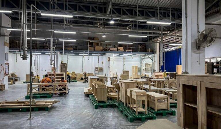 โถงผลิตหลักของโรงงาน Planet Furniture ชลบุรี มีเฟอร์นิเจอร์ไม้ที่กำลังผลิตวางเรียงบนพาเลท