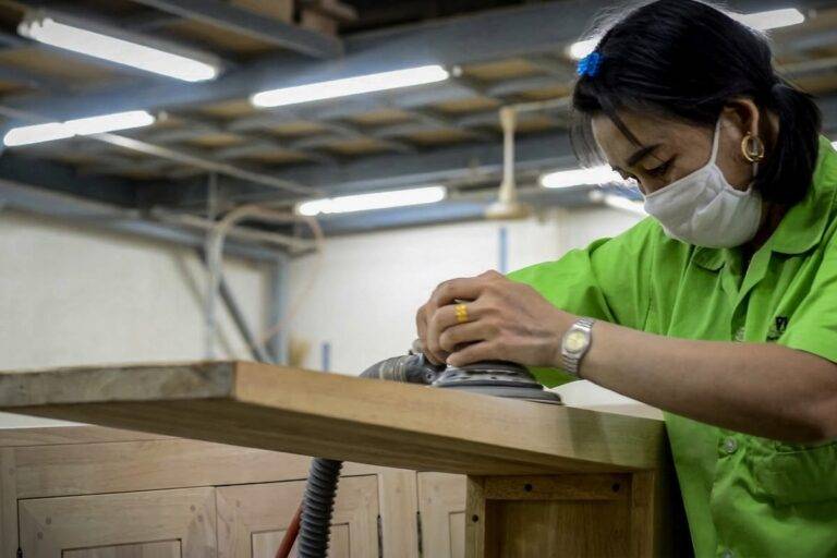 พนักงานขัดผิวแผ่นไม้ยางพาราในขั้นตอนตรวจคุณภาพที่โรงงาน Planet Furniture